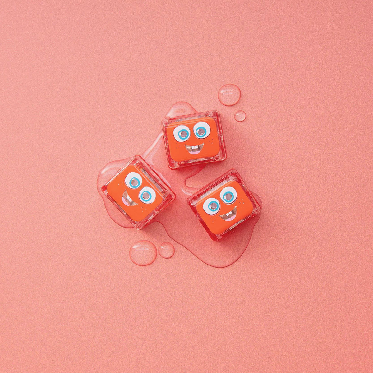 Three Glo Pals Sammy light-up cubes on a pink background with water droplets