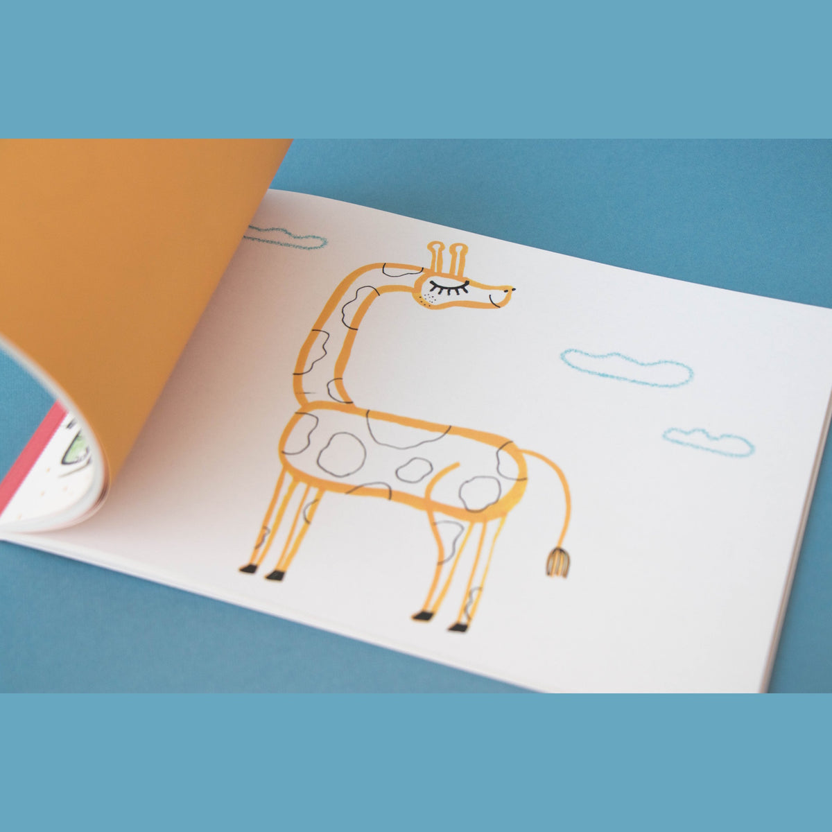 Whimsical giraffe illustration in a Londji art activity book for kids, featuring simple lines and blue clouds.