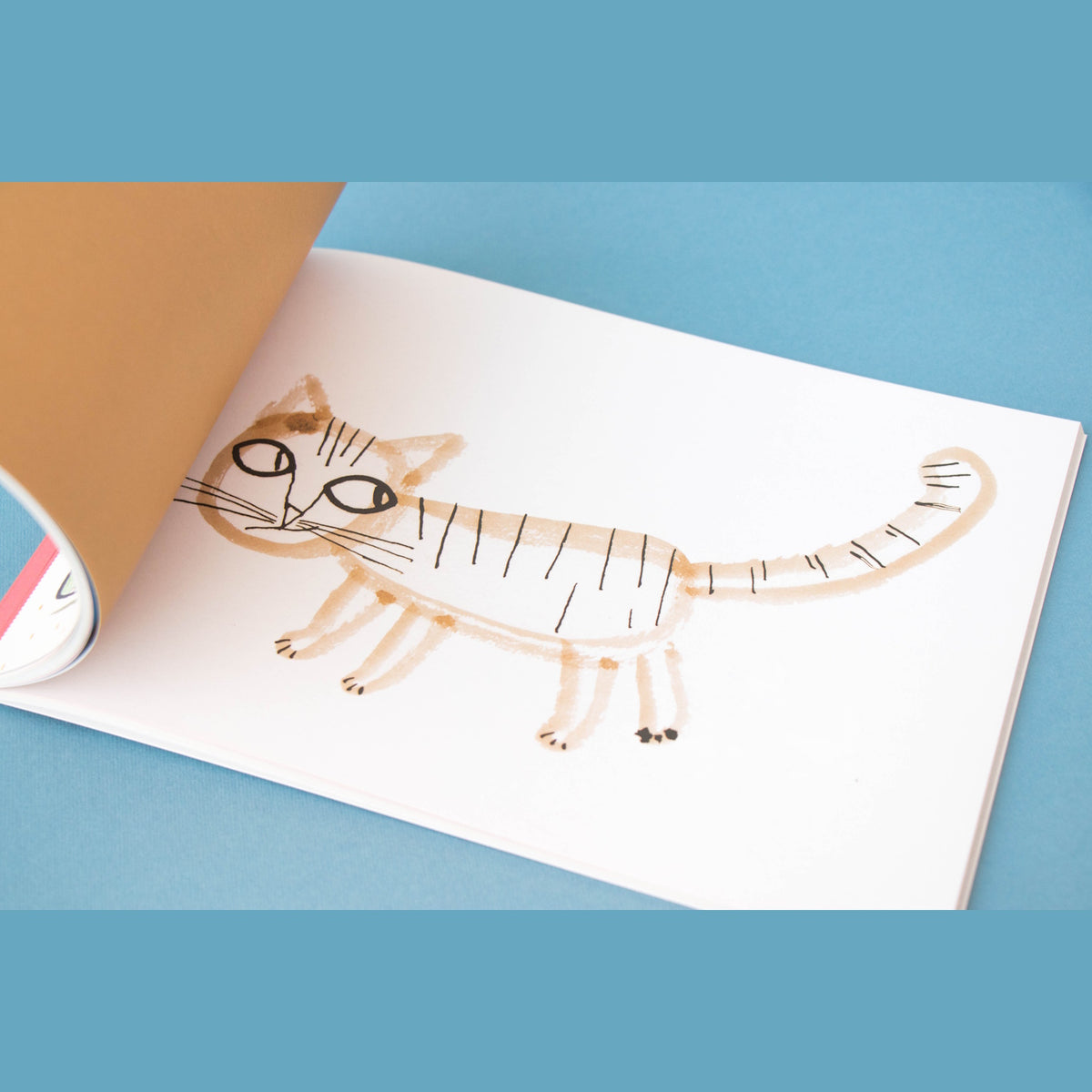 Whimsical watercolor illustration of a striped cat in a Londji art activity book, featuring simple brown and black strokes.