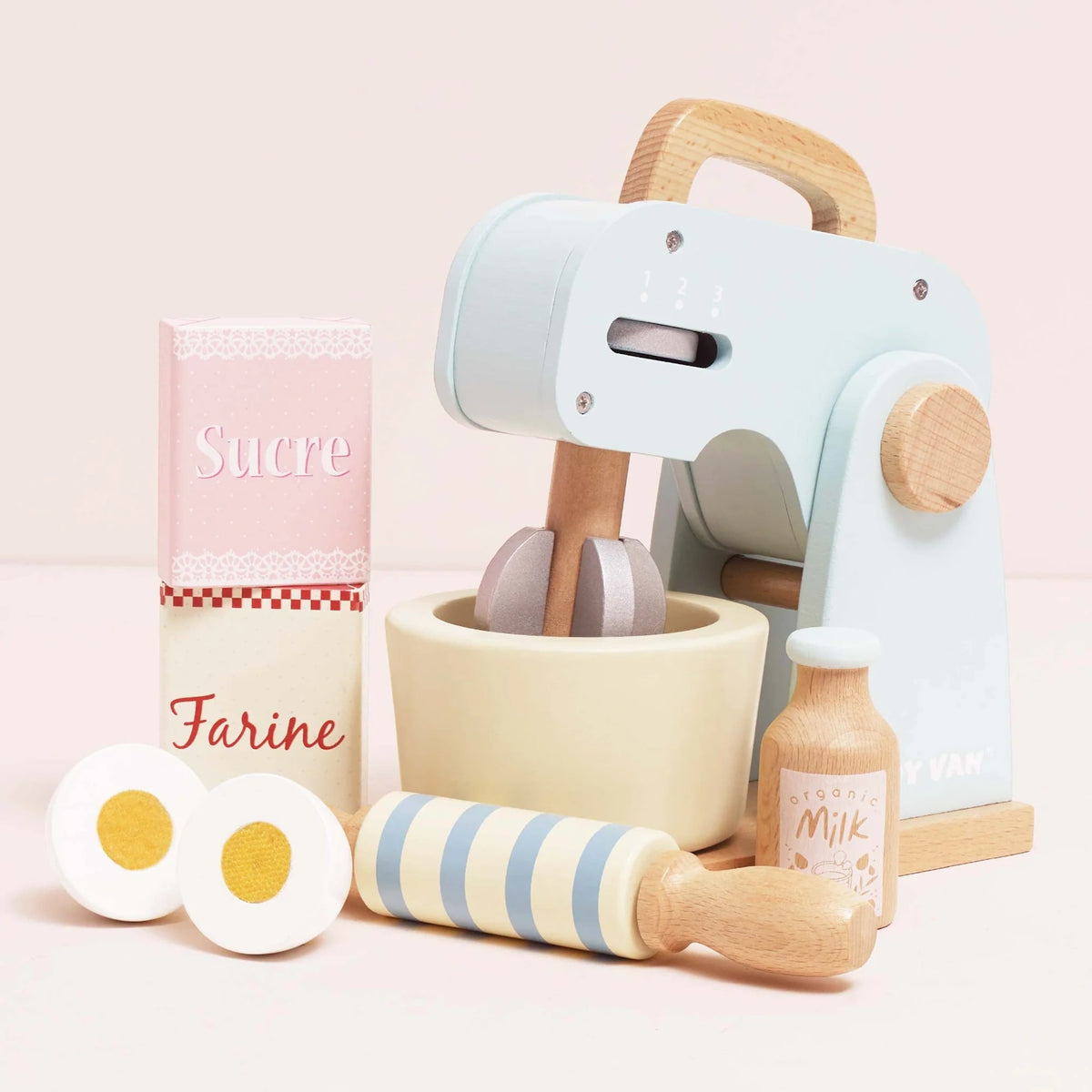 Wooden toy baking set including a pastel blue mixer, bowl, rolling pin, milk bottle, eggs, and ingredient boxes.