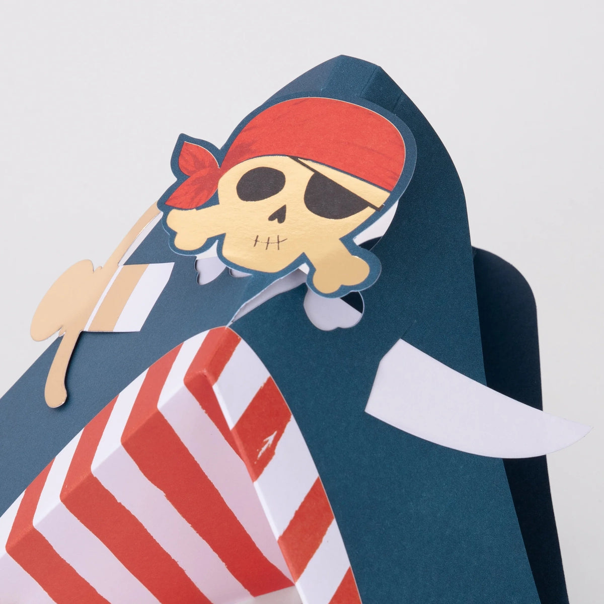 A blue paper shark craft wearing a pirate skull and crossbones emblem with a red bandana.