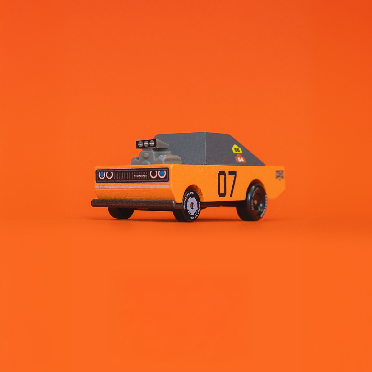 Orange and grey Candycar Storm Duke muscle car toy with a large engine hood scoop and number 07 on an orange background.