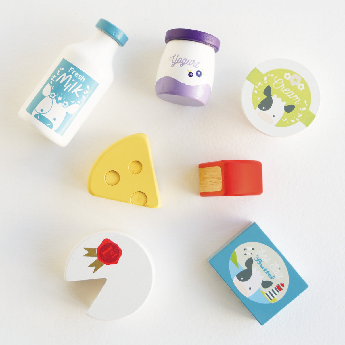 Scattered toy dairy items and cheeses on a white background.