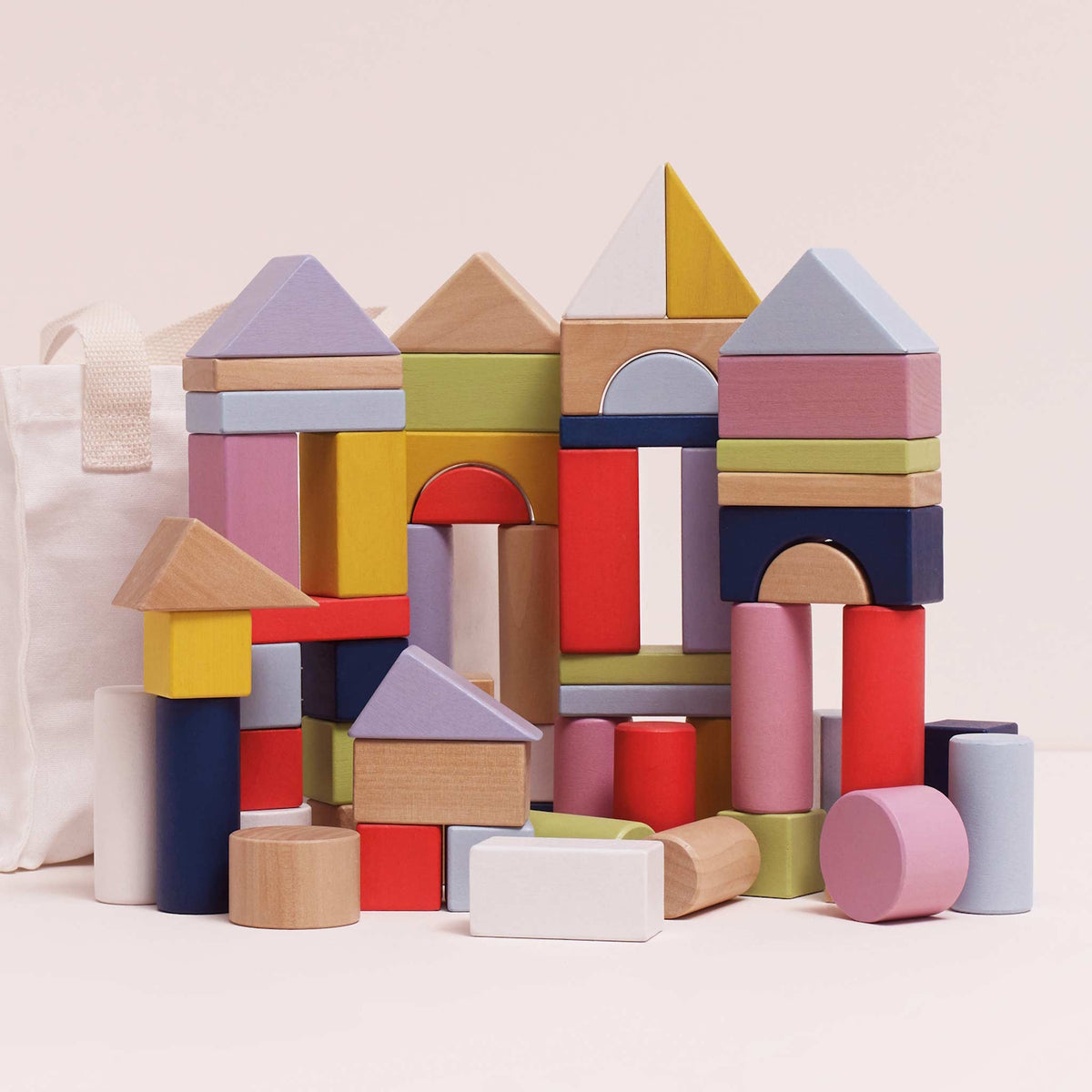 Colorful wooden building blocks stacked into castle towers next to a fabric storage bag.