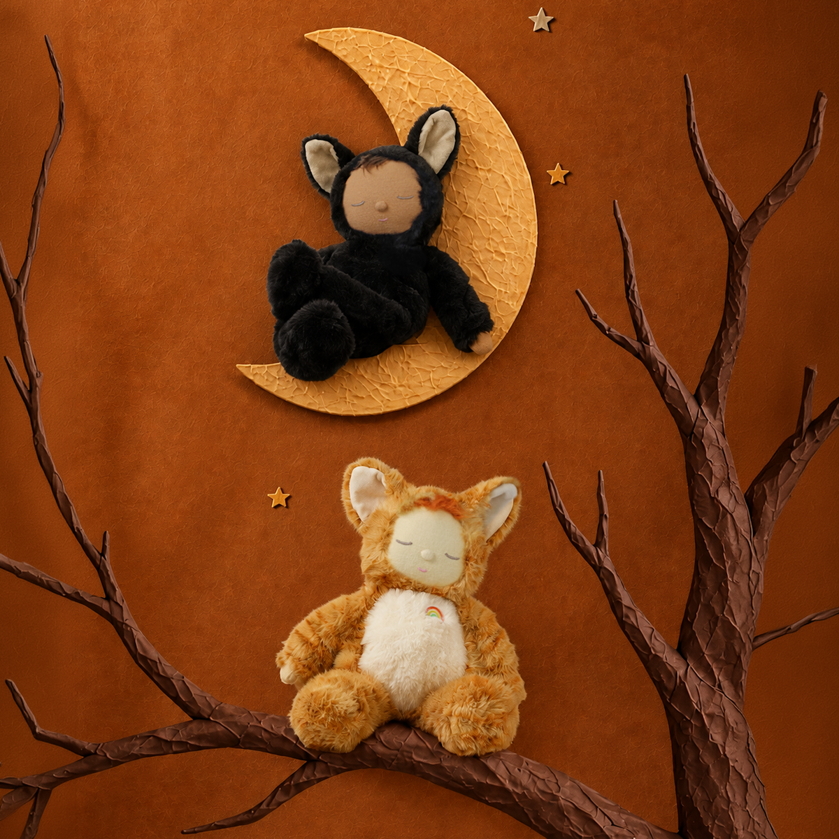 Two sleeping cat plush dolls in black and orange suits set against a crescent moon and tree branches.