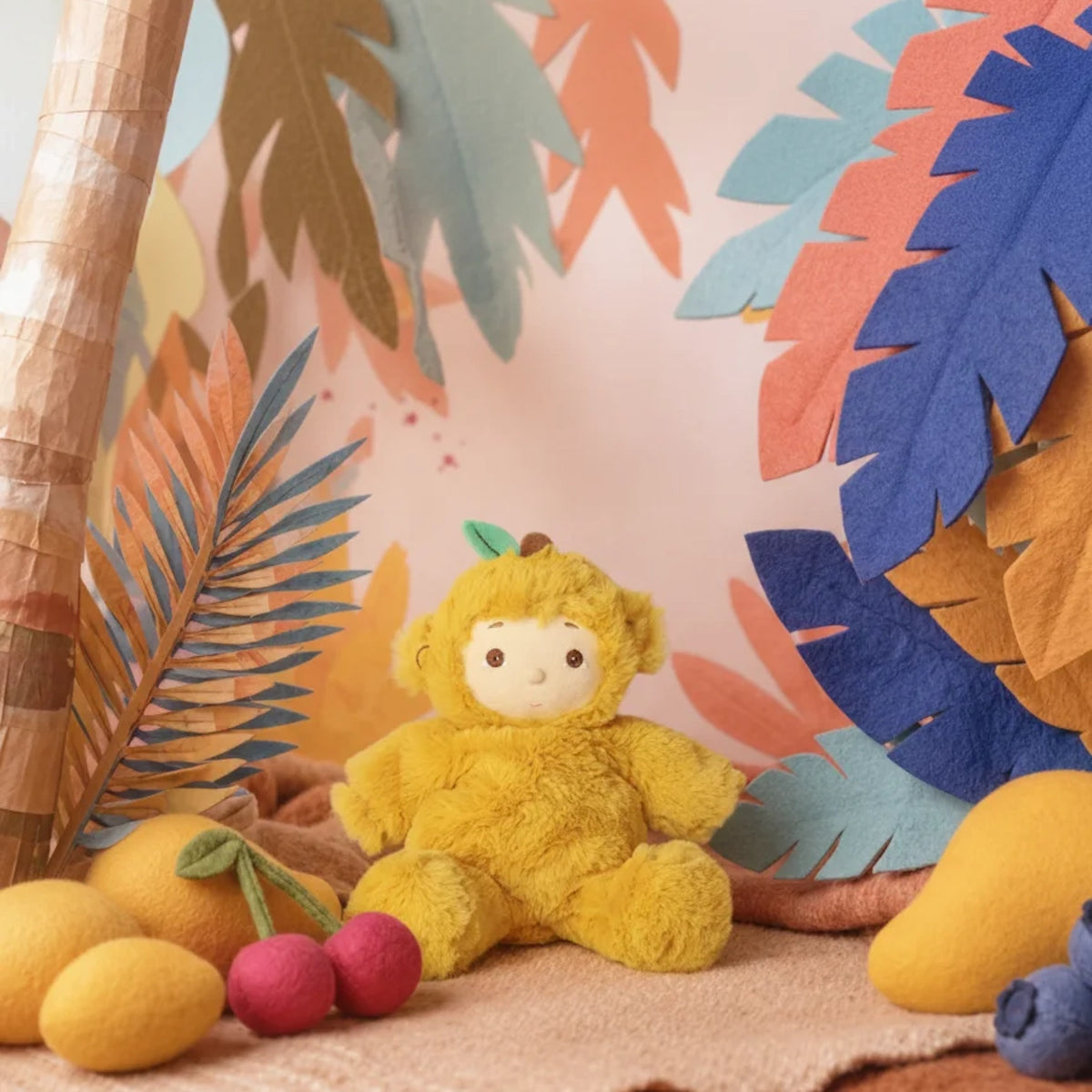 Olli Ella Cozy Dinkum Doll Mango Monkey plush toy sitting in a colorful jungle setting.