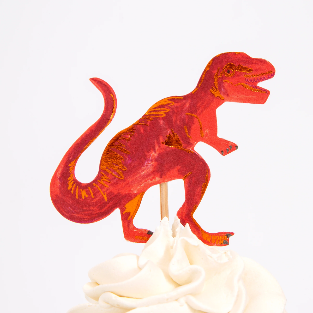 Red T-Rex dinosaur cupcake topper on a wooden pick in swirled white frosting.
