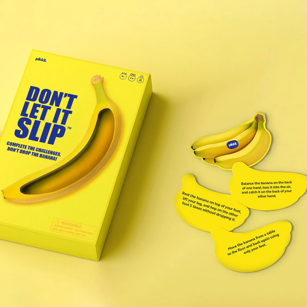 Yellow "Don't Let It Slip" party game box next to banana-shaped challenge cards on yellow background.