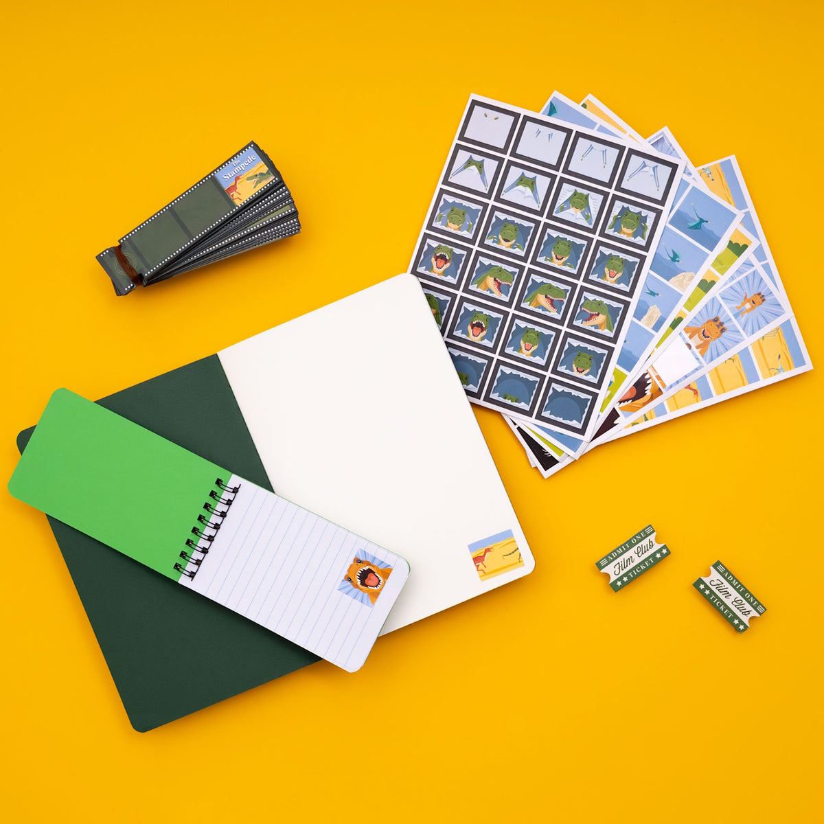 Dinosaur animation flip book kit with stickers, notebooks, film strips, and tickets on a yellow background.