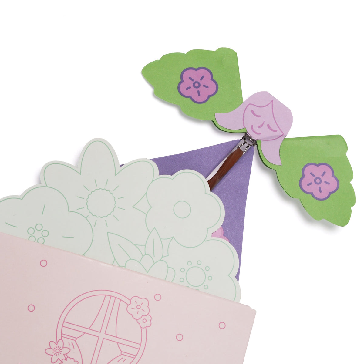 Paper flying fairy toy with green wings emerging from a floral-patterned envelope.