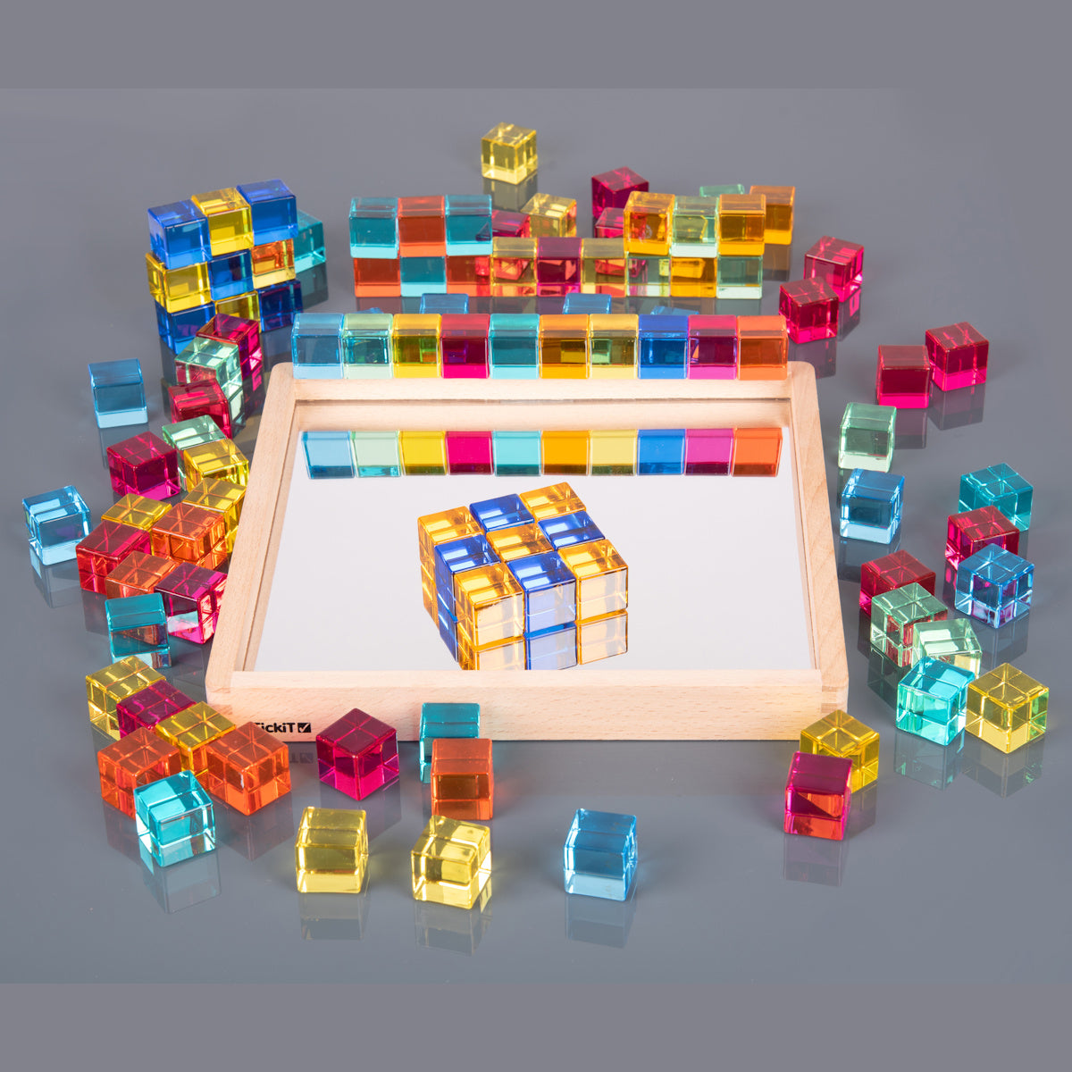 A square wooden tray with a mirrored base and colorful gem-like insets, designed to inspire sensory exploration, pattern making, and visual play.