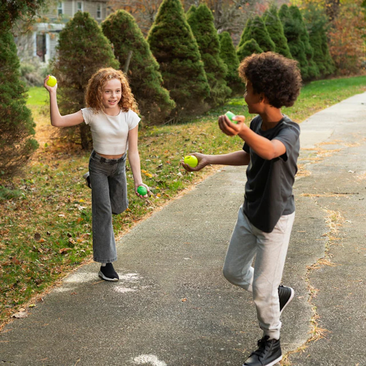 Two kids playing outside with Huckleberry reusable water balls on a paved path.