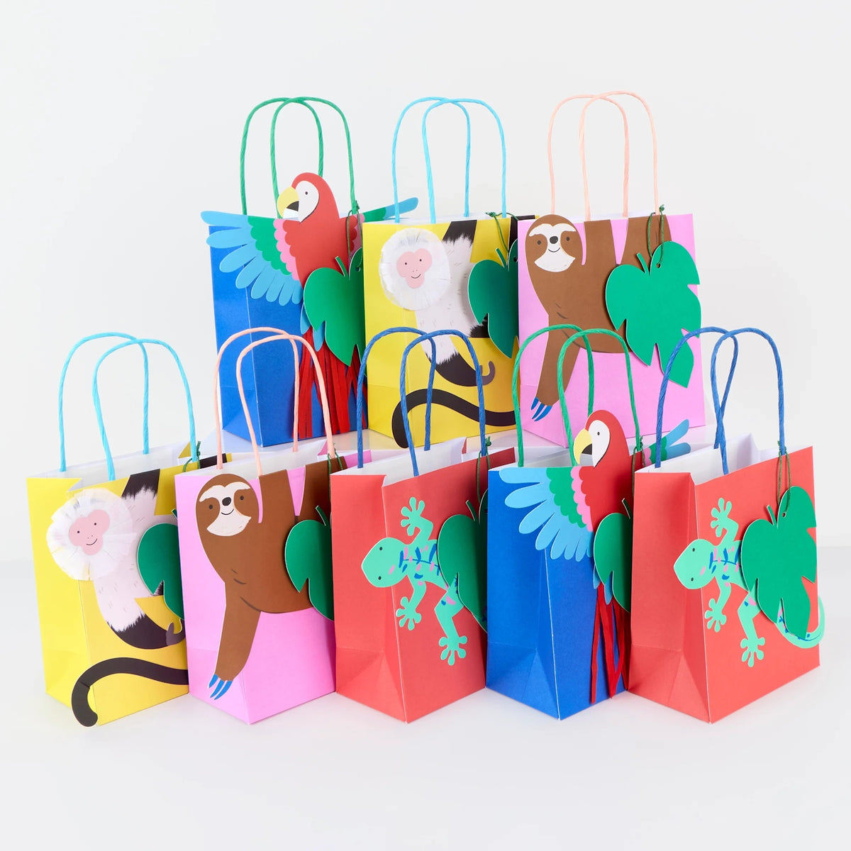 Colorful jungle-themed gift bags featuring paper cutouts of parrots, sloths, monkeys, and geckos.