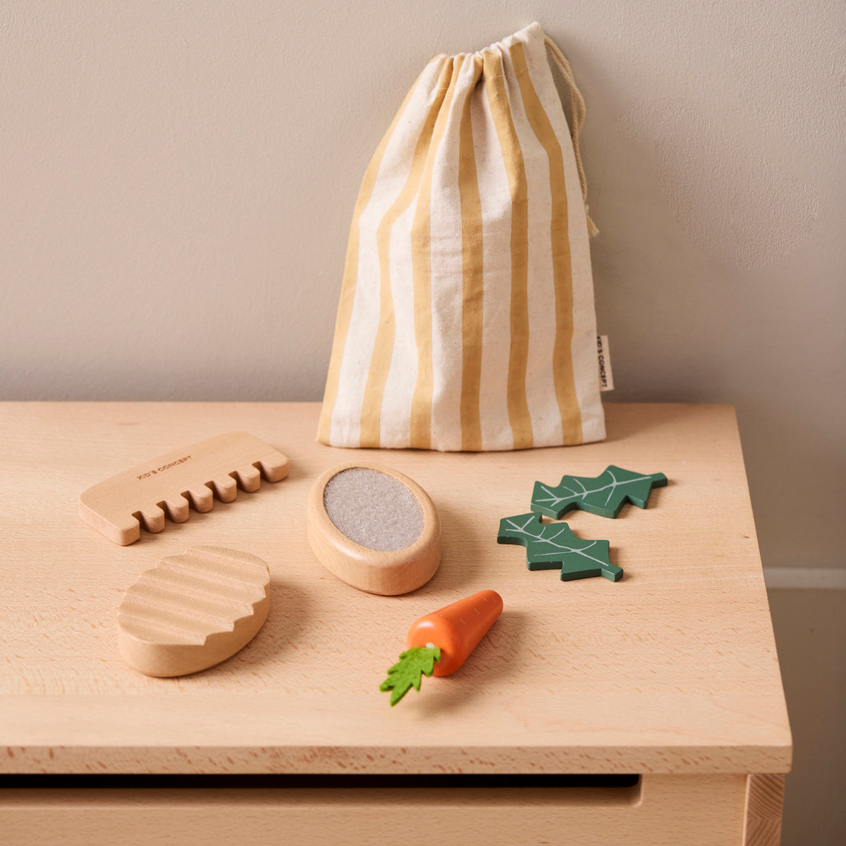 Wooden pet care toy set with grooming tools, toy food, and a striped drawstring bag on a surface.