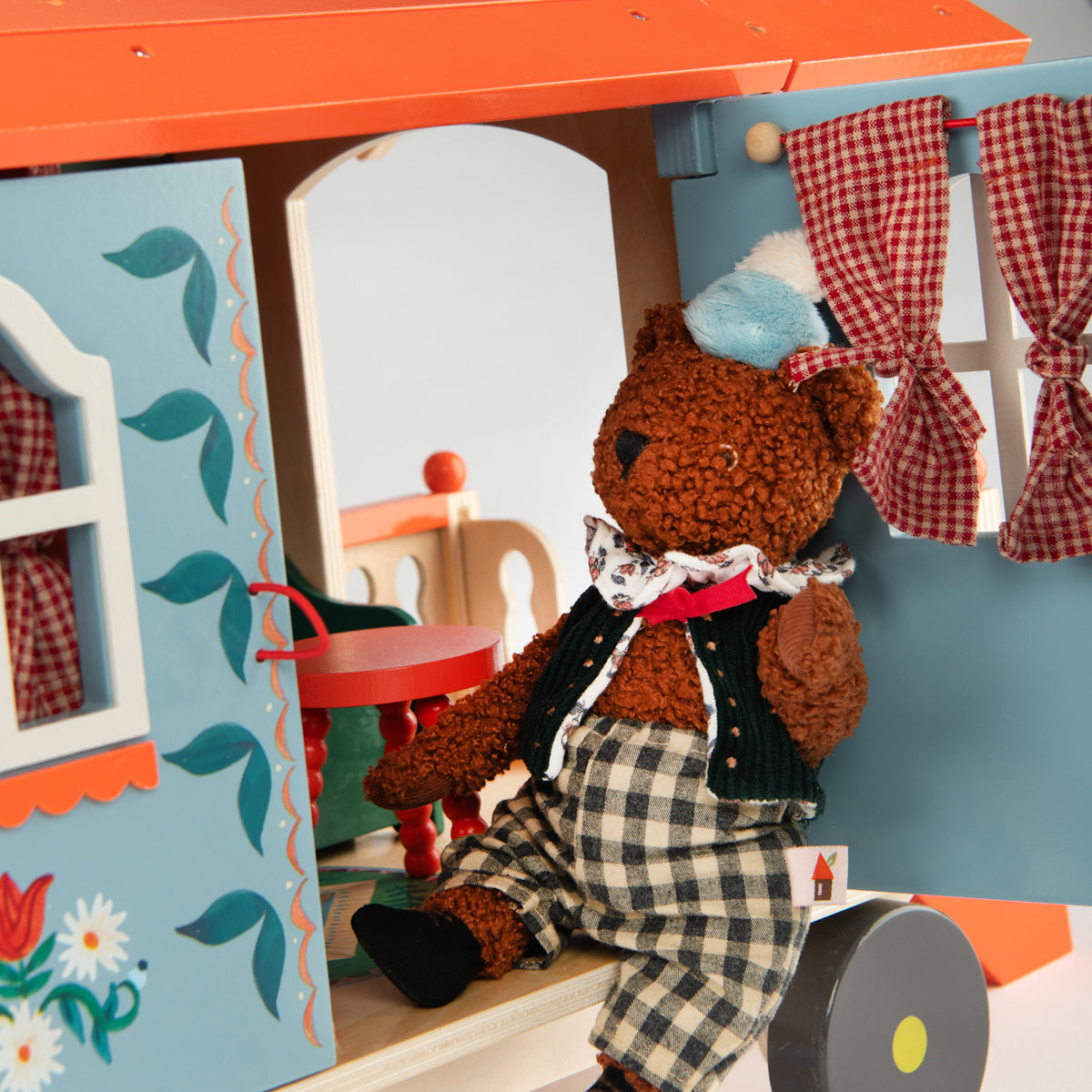 Les Minouchkas toy teddy bear sitting on the wooden caravan steps.