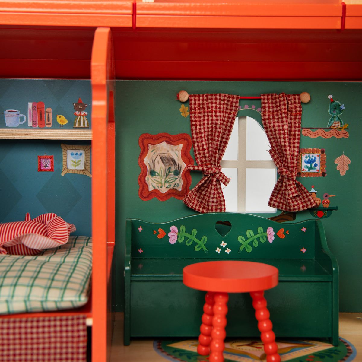 Wooden dollhouse interior with green bench, red table, plaid curtains, and miniature bedroom.