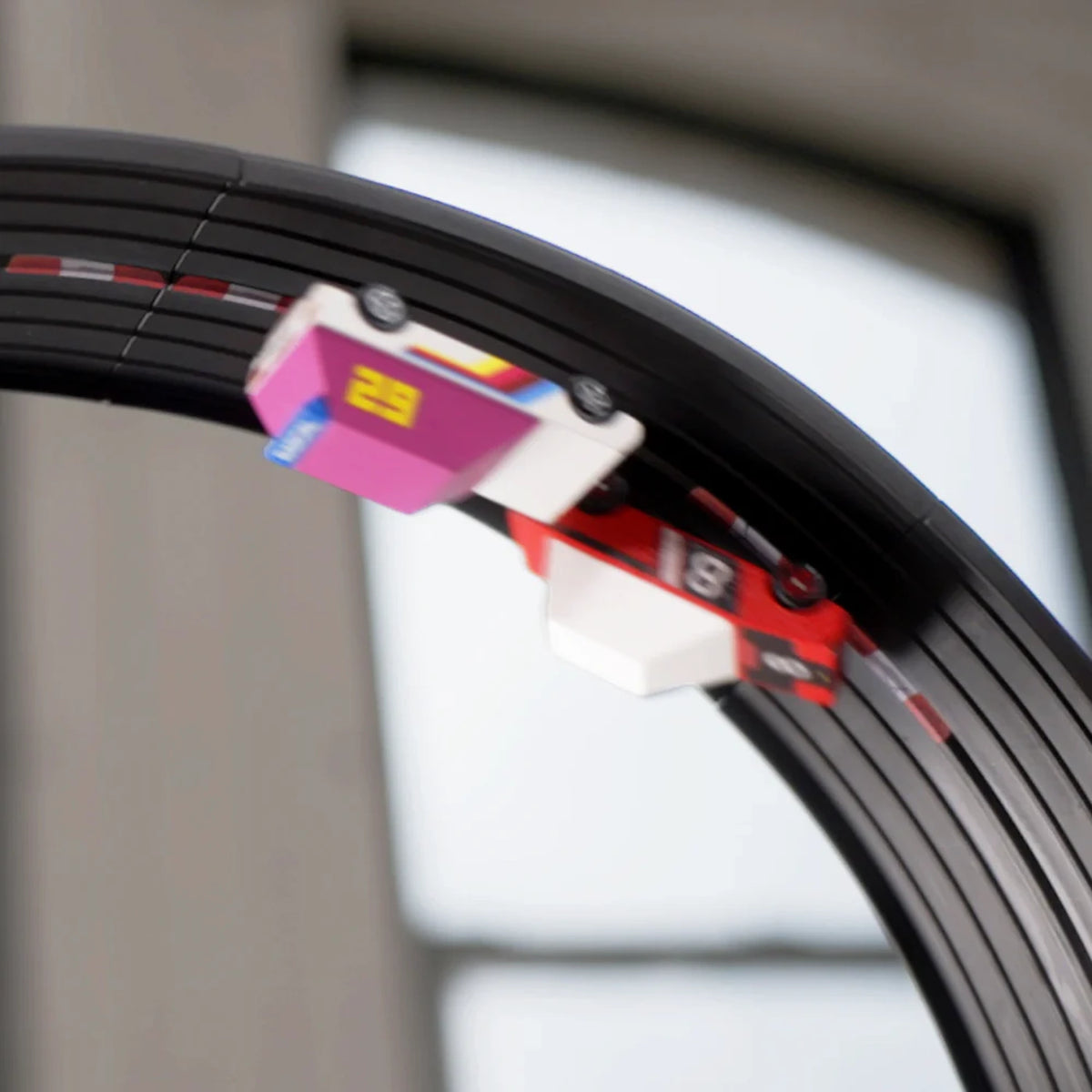 Action shot of Candylab toy cars racing upside down on a black Roadworks Loop track add-on kit.