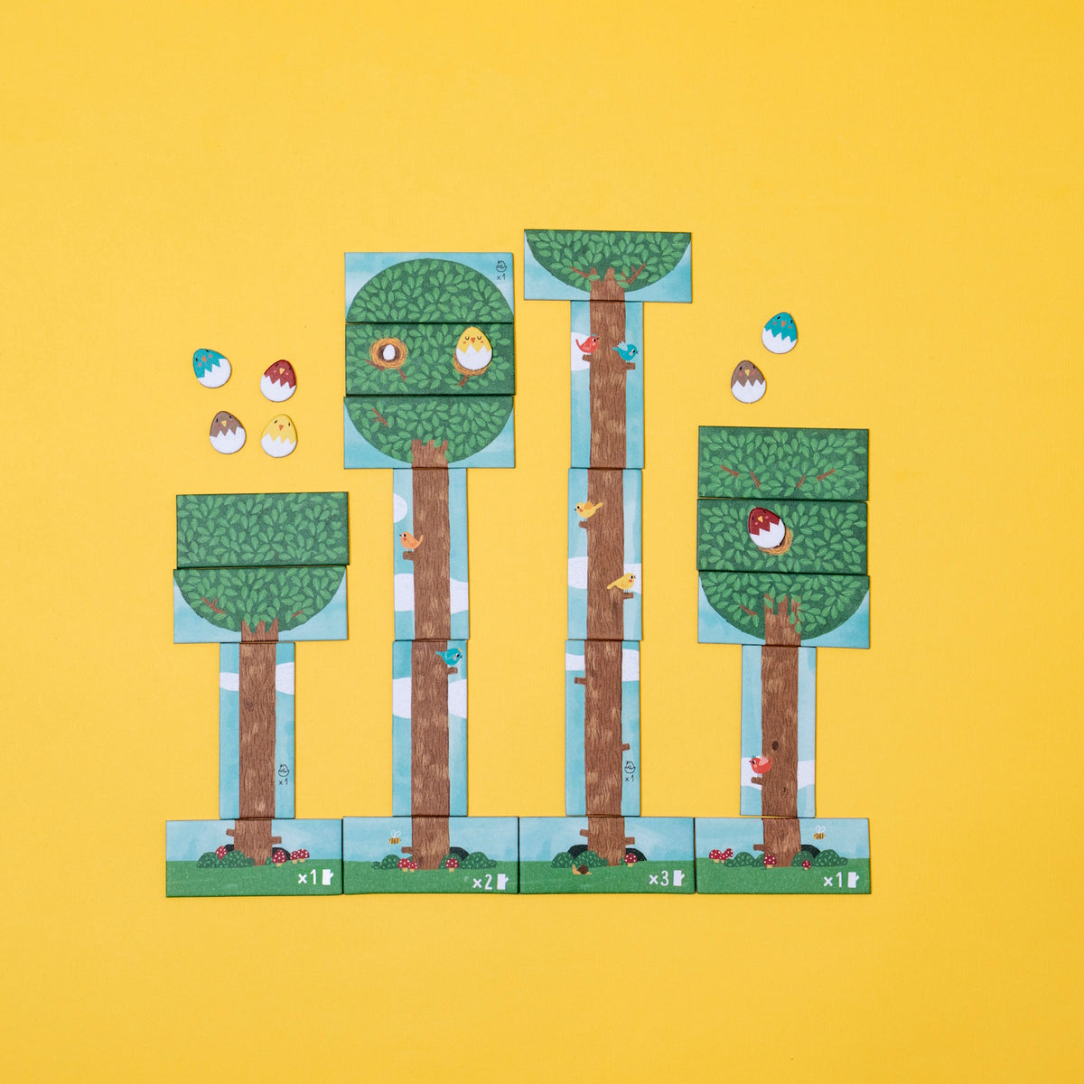 Colorful bird card game with illustrated trees, birds, and egg tokens on a bright yellow background.
