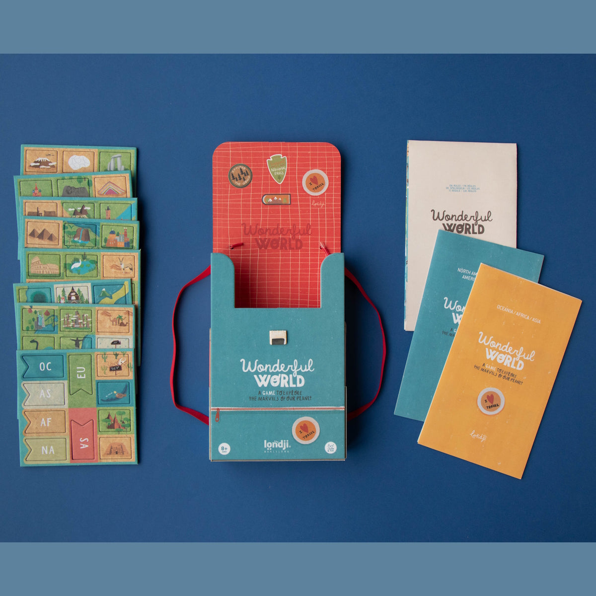 Londji Wonderful World board game components including illustrated cards, continent tokens, and booklets on a blue background.
