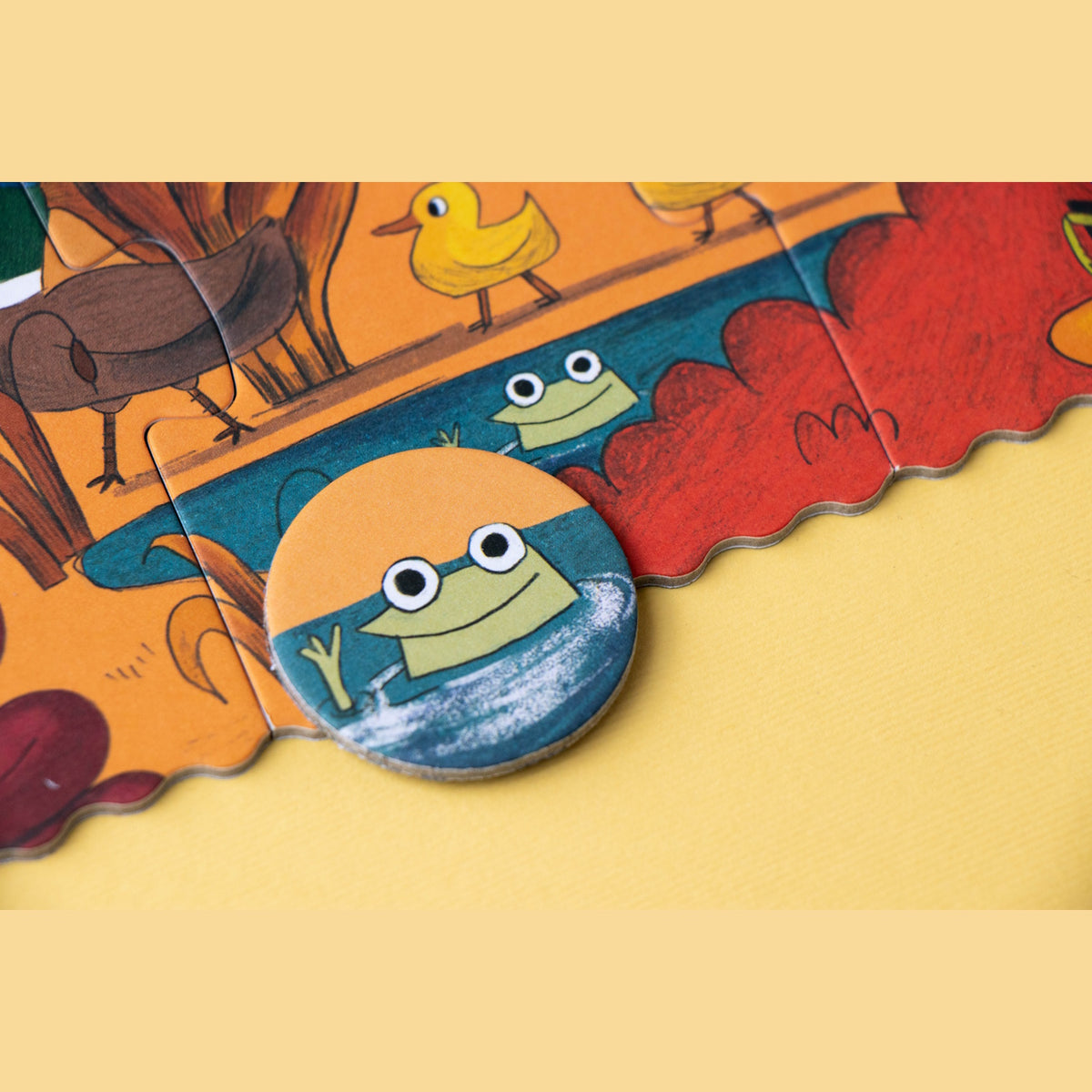 Londji forest jigsaw puzzle featuring a pond with a frog and a matching round frog game token.