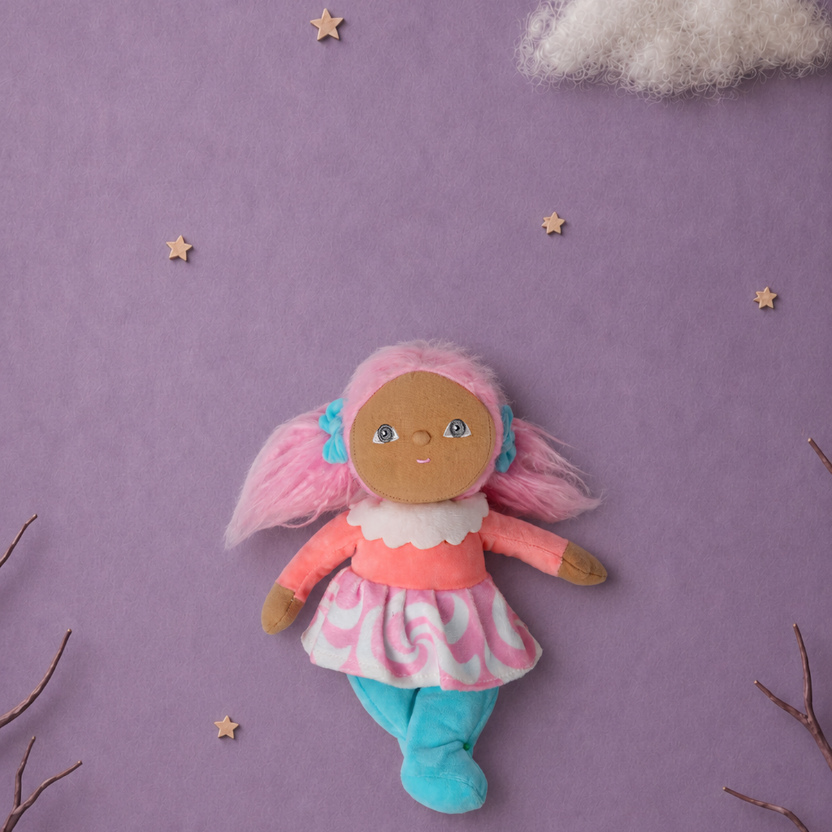 Plush doll with pink pigtails centered on a lavender background with stars and clouds.