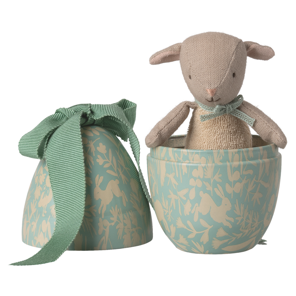 A soft, beige toy rabbit peeks out of a half-open, patterned blue egg-shaped box adorned with white floral designs and a green ribbon, set against a white background.