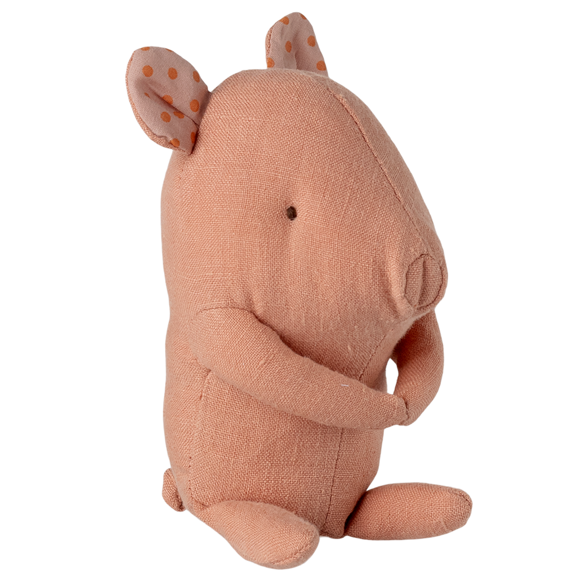 A soft, peach-colored fabric pig toy with small eyes and floppy ears featuring orange polka dots, sitting against a white background.