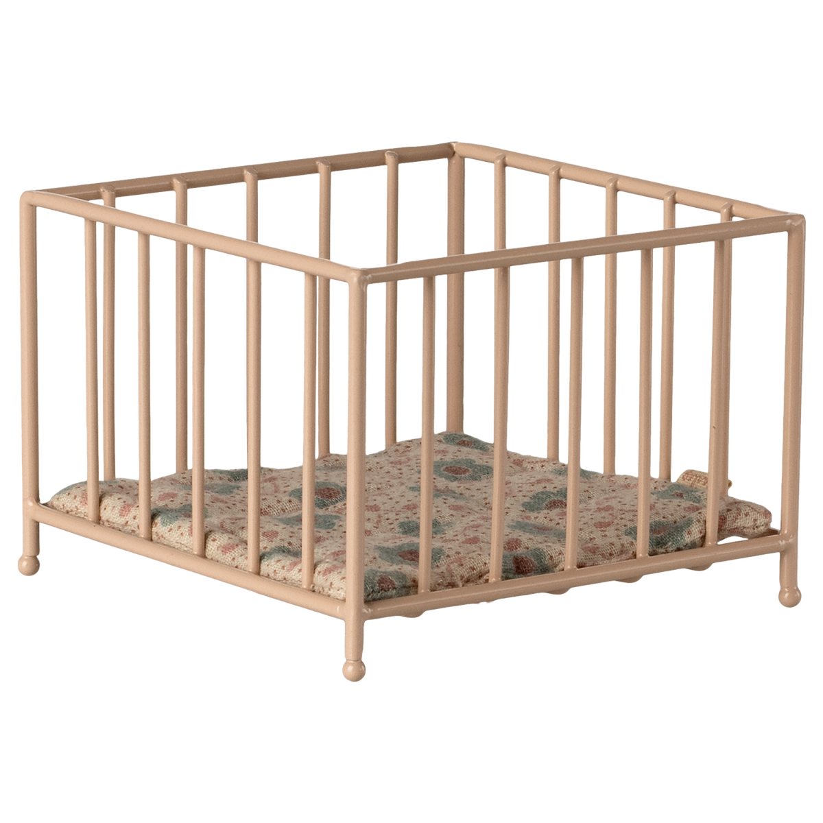A small, beige metal playpen with a colorful, quilted cushion sits empty against a white background, conveying a sense of simplicity and nostalgia.