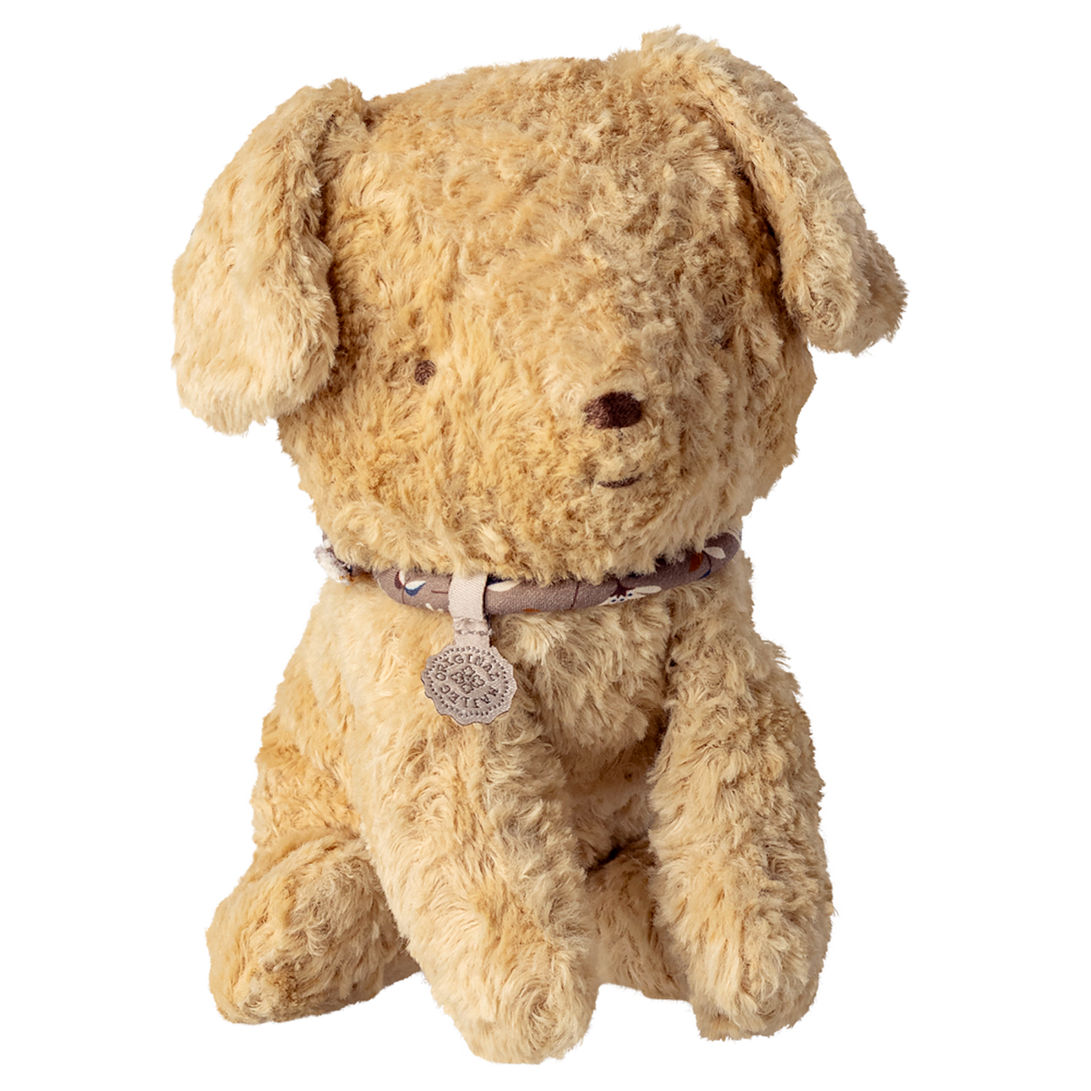 A plush teddy bear with light brown fur sits against a white background. It wears a decorative collar with a round pendant, conveying warmth and charm.