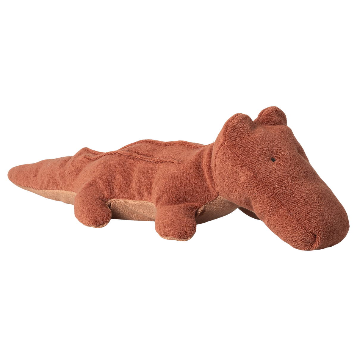 A brown plush crocodile toy lies on a white background. The toy has a soft, textured surface with a whimsical, friendly expression, conveying a playful mood.