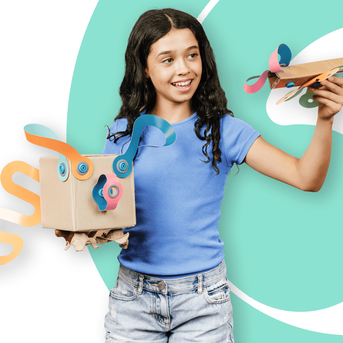 A smiling girl holding custom cardboard craft toys decorated with colorful paper twists and blue connectors.