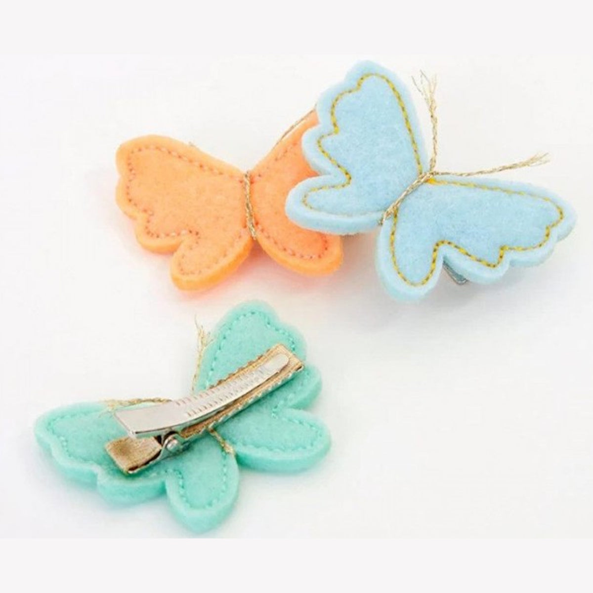 Three Meri Meri felt butterfly hair clips in peach, light blue, and mint green with gold thread antennae.
