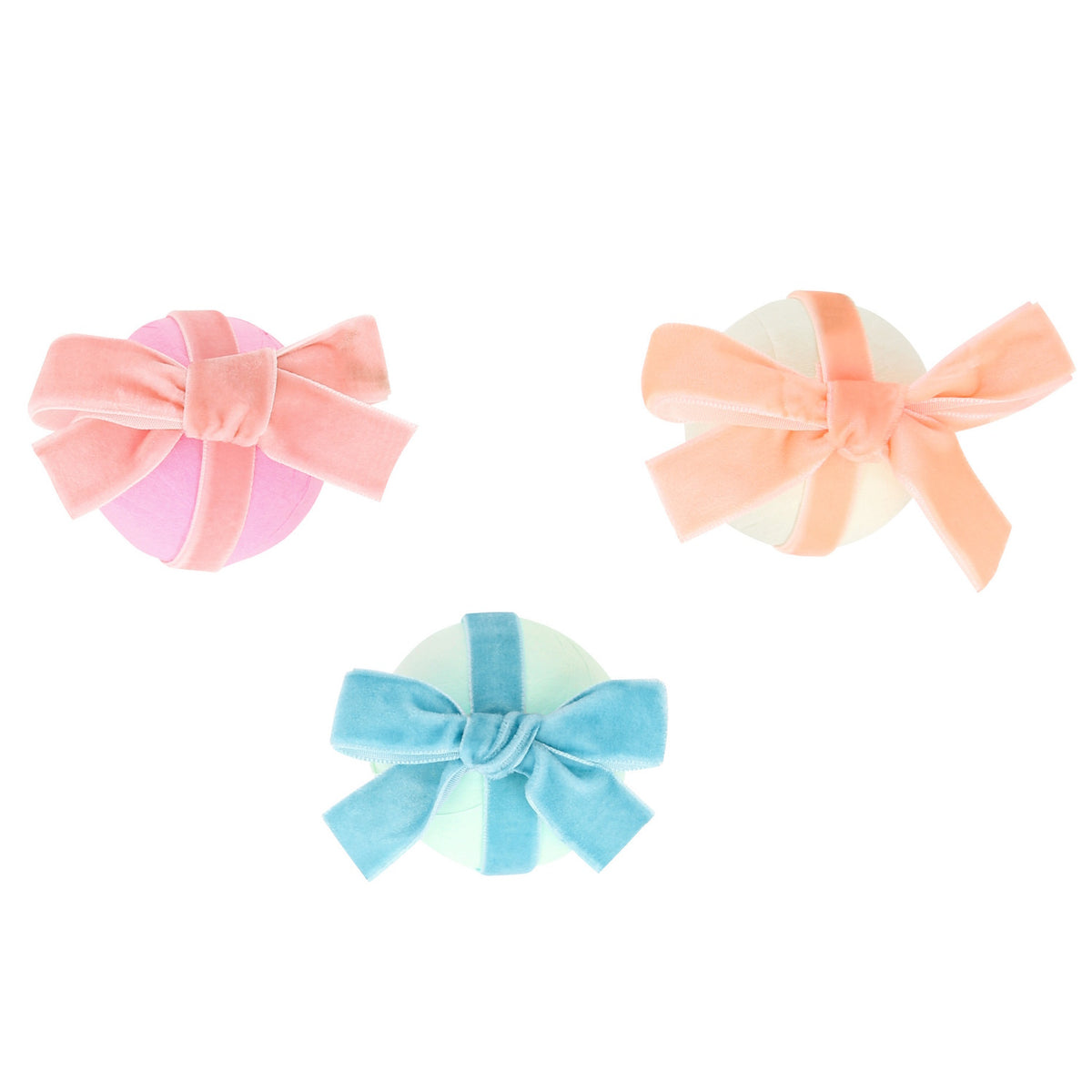 Three pastel surprise balls wrapped in velvet bows, featuring pink, peach, and blue ribbons on a white background.