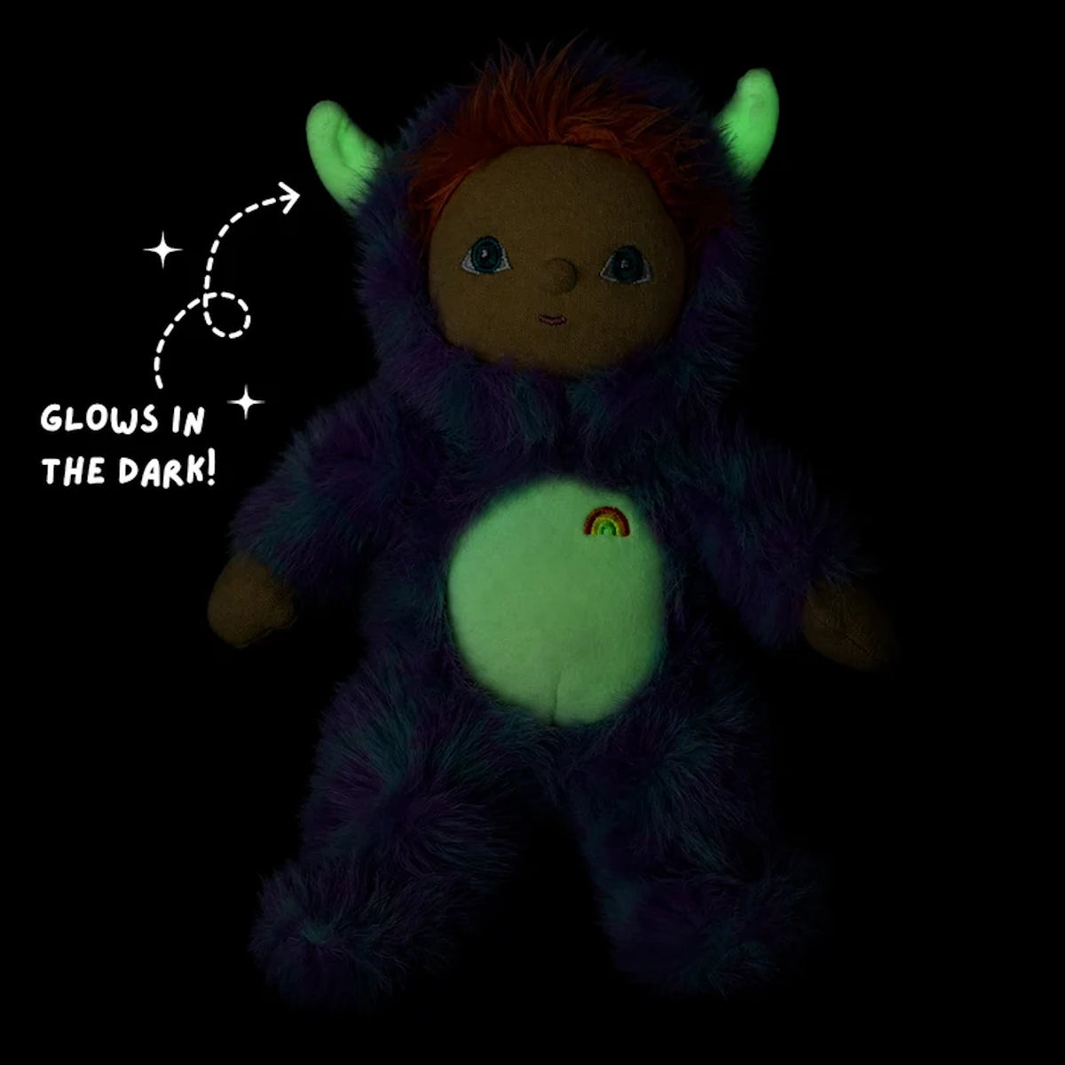 Plush doll in dark showing glow-in-the-dark horns and belly patch with "GLOWS IN THE DARK!" text.