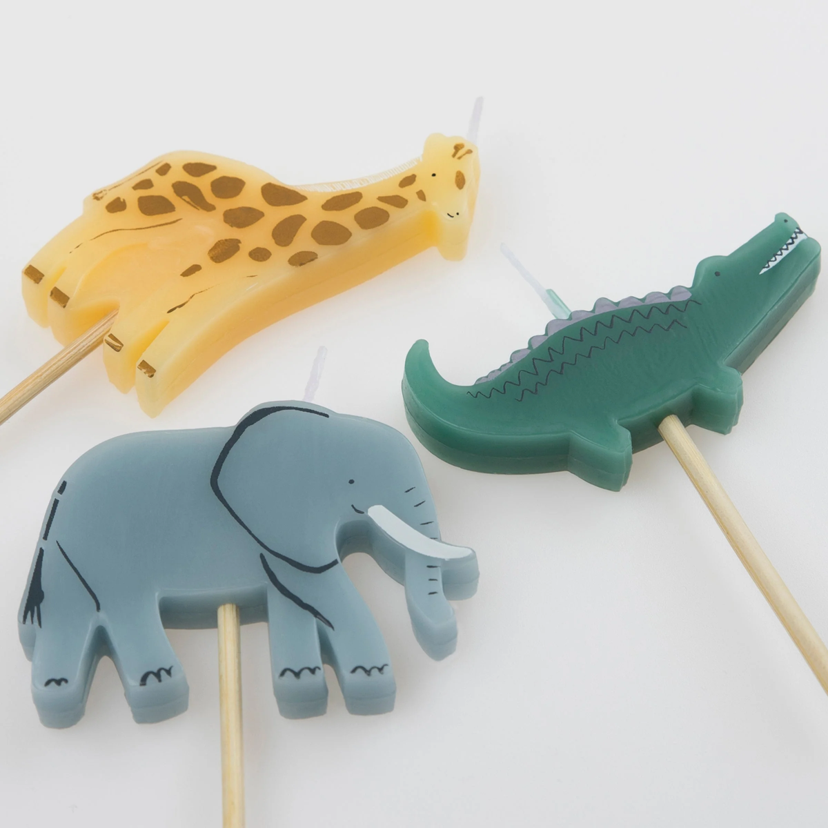Close-up of three safari animal birthday candles shaped like a giraffe, crocodile, and elephant.