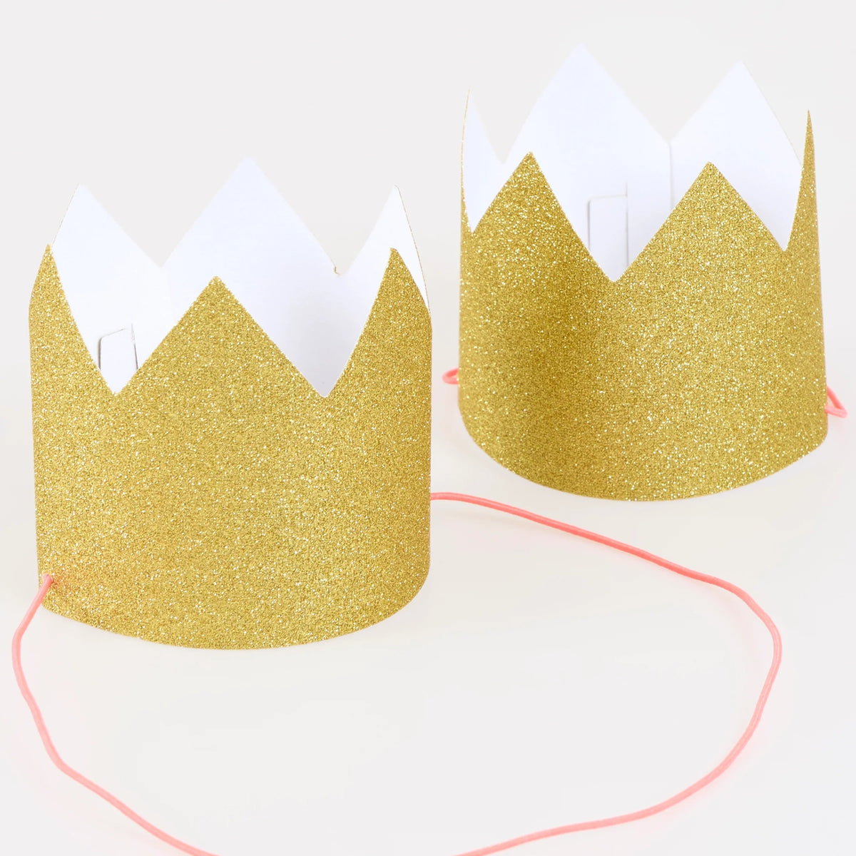 Two mini gold glitter party crowns with pink elastic straps on a white background.