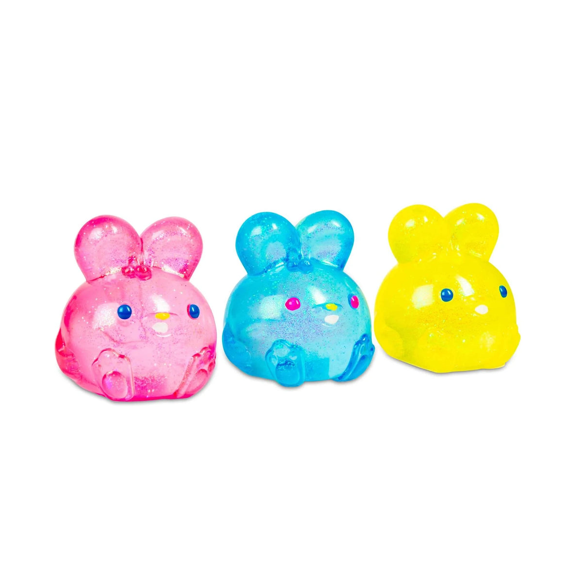 Three cute, translucent bunny toys in pink, blue, and yellow are lined up. They have sparkling textures and small, colorful facial features, conveying a playful vibe.