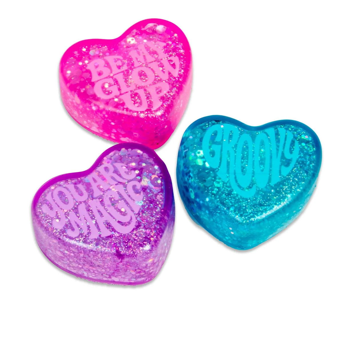 Three glittery heart-shaped objects in pink, blue, and purple. Text reads: "Be My Glow Up," "Groovy," and "You Are Magic," conveying positivity.