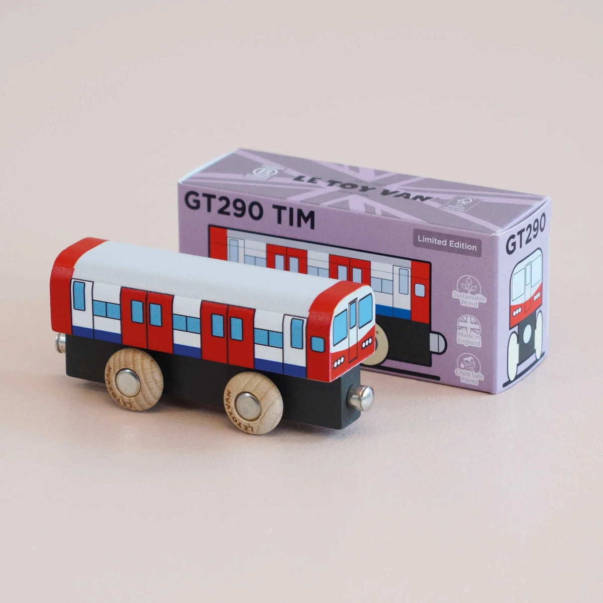 Red, white, and blue wooden toy train carriage angled in front of its GT290 TIM product box.
