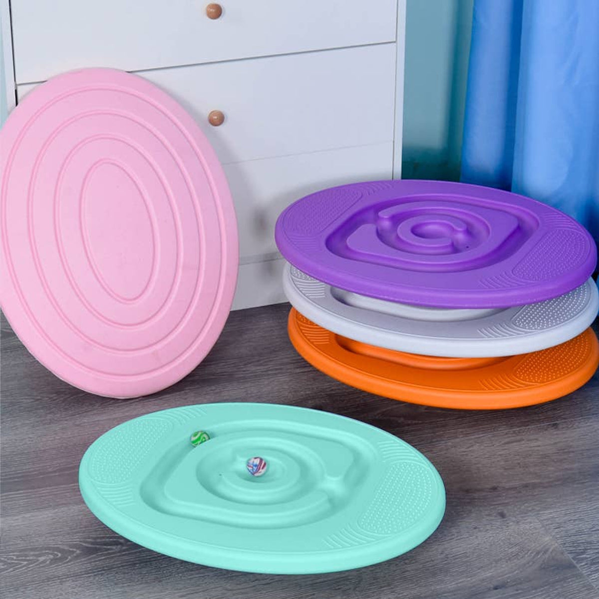 Assorted colorful sensory balance maze boards displayed on a floor next to a white drawer.