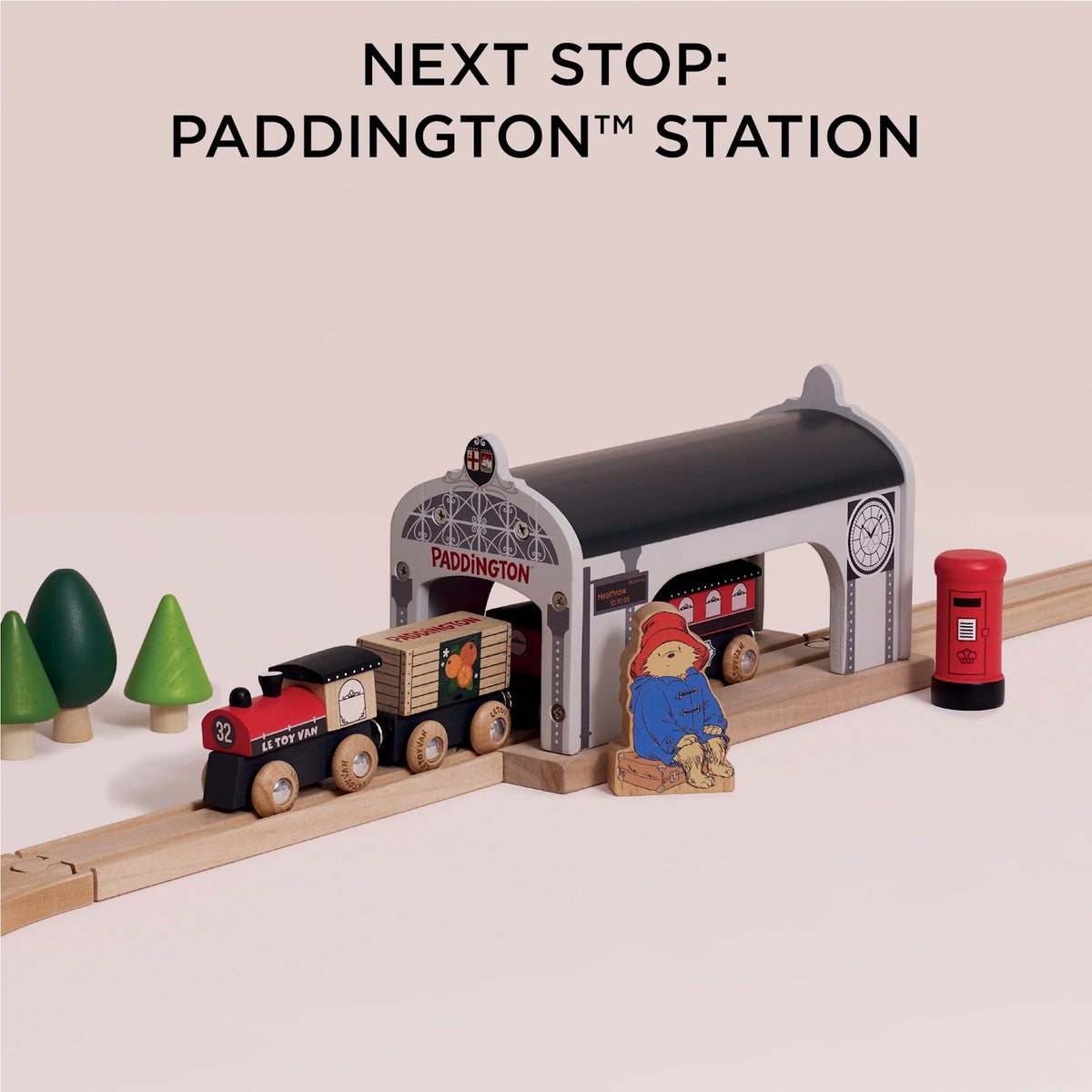 Wooden train pulled up to Paddington station with a Paddington Bear figurine and red post box.