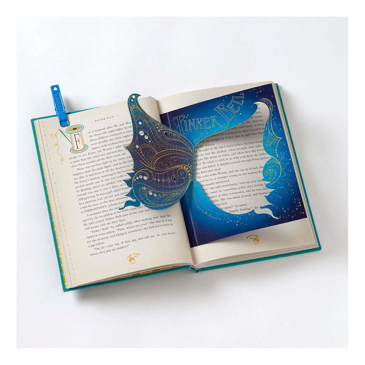 Open Peter Pan book featuring an intricate blue and gold Tinker Bell pop-out wing illustration on text-heavy pages.
