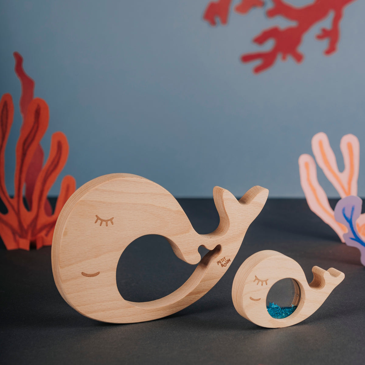 Wooden whale and baby puzzle pieces displayed against an underwater-themed backdrop.