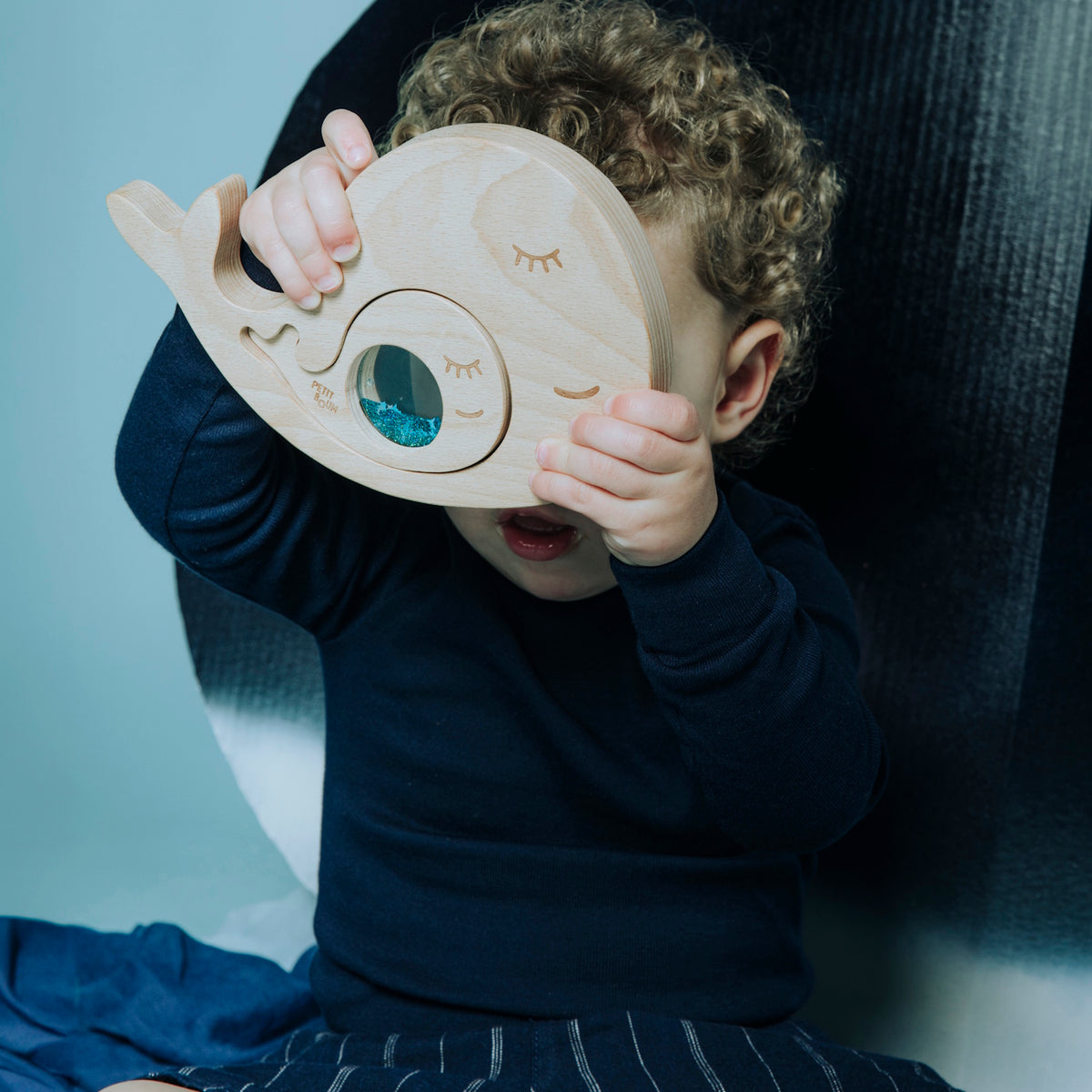 Toddler holding the whale sensory puzzle up to their face.