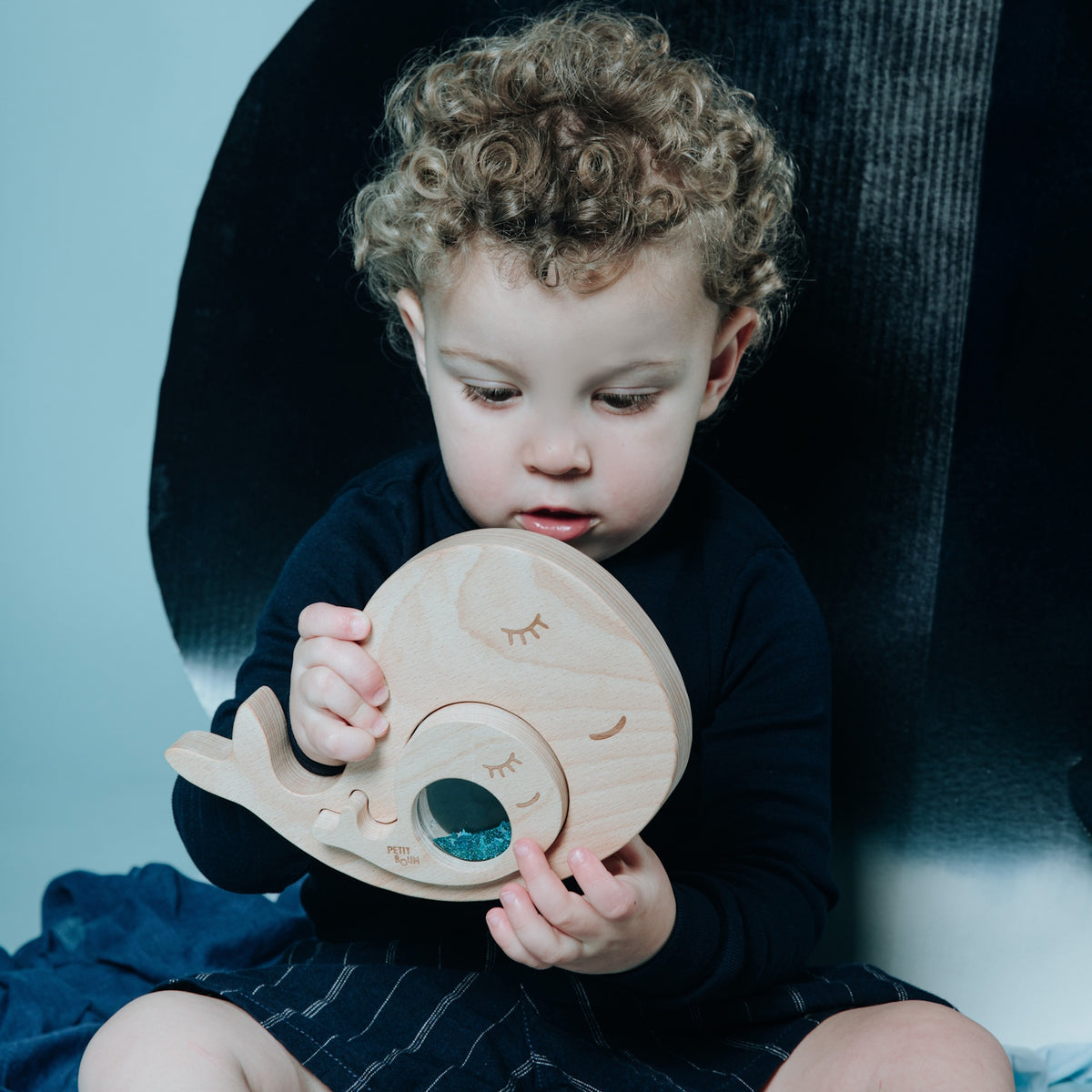 Toddler holding and looking at the whale sensory puzzle.