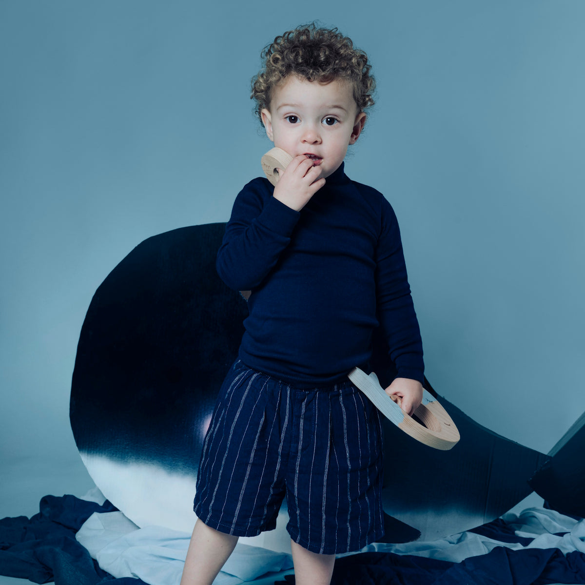 Toddler standing and holding pieces of the whale sensory puzzle.