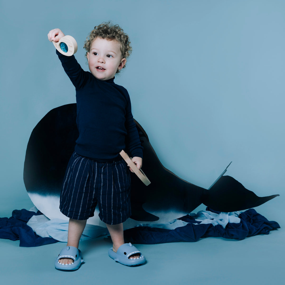 Toddler standing and holding up a piece of the whale sensory puzzle.