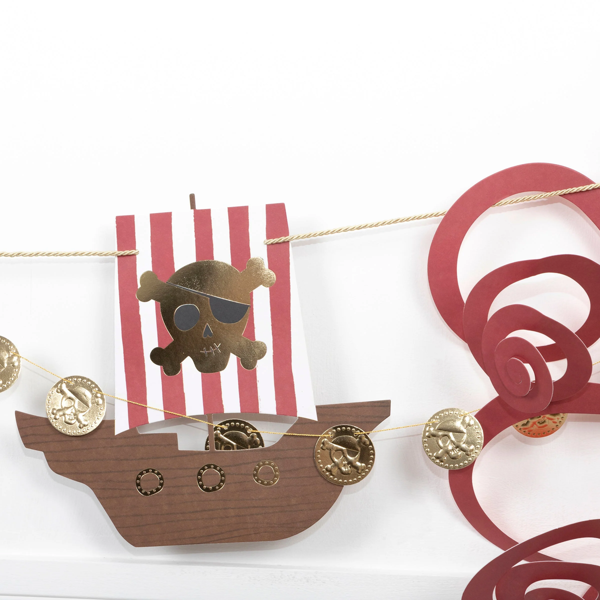 Close-up of a pirate garland showing a paper pirate ship cutout, gold coin garland, and red octopus tentacles.