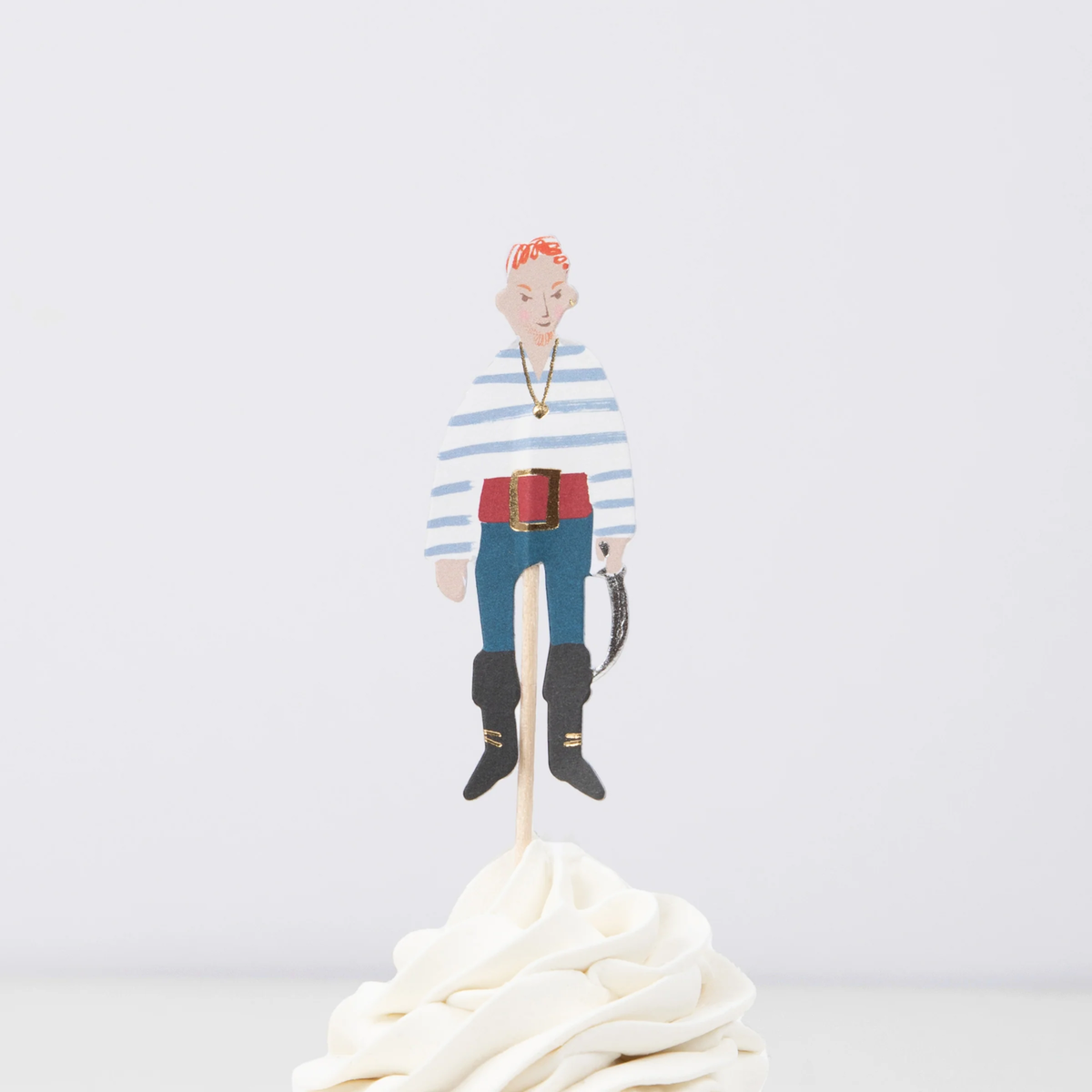 Pirate crew member topper in a striped shirt and red belt on a wooden pick in swirled white frosting.