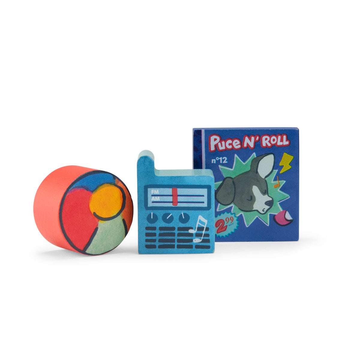 Three small wooden toy blocks: a red cylinder with a beach ball, a blue radio, and a square "Puce N' Roll" dog record.